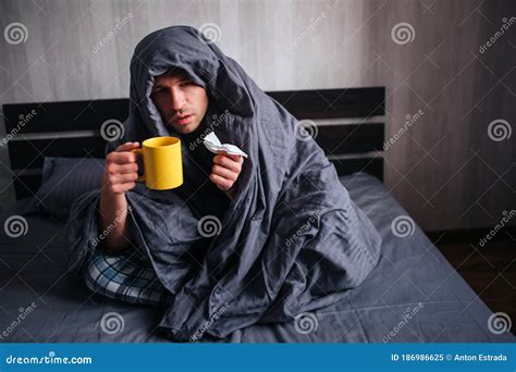 He Covered Himself With A Blanket And Holds A Napkin And Hot Tea The