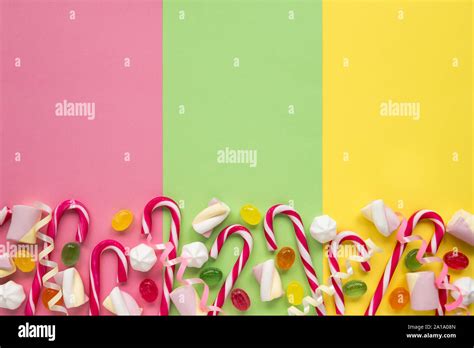 Some Candy Canes Marshmallows And Meringues Are Scattered On Colored