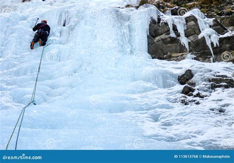 Male Mountain Guide Lead Ice Climbing A Frozen Waterfall In Deep Winter