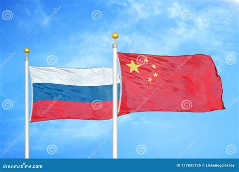 Russia And China Two Flags On Flagpoles And Blue Cloudy Sky Stock Image