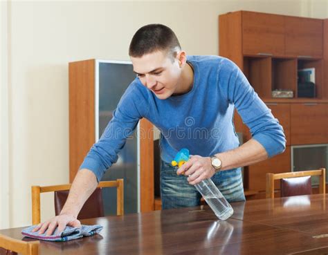 Guy Dusting Wooden Table With Rag And Cleanser At Home Stock Image