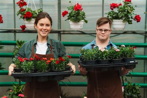 Hombre Con Síndrome De Down Y Mujer Sonriendo Y Sujetando Plantas