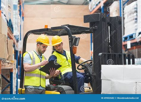 Trabajador De Warehouse Que Habla Con El Conductor De La Carretilla