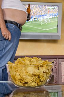 Man With Naked Beer Belly Holding Beer Bottle In Front Of Flatscreen Tv