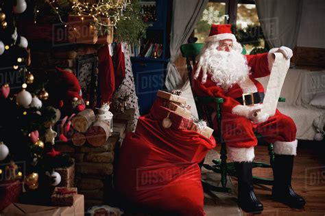 Portrait Of Santa Claus Sitting In Chair With Sack Full Of Presents