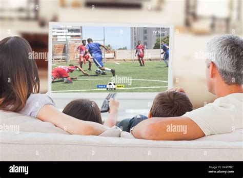 Familia caucásica viendo la televisión con un partido de fútbol en la