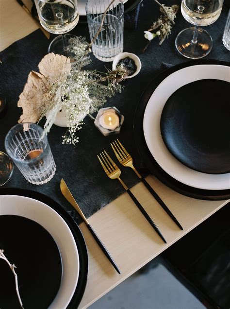 The Table Is Set With Black Plates And Silverware