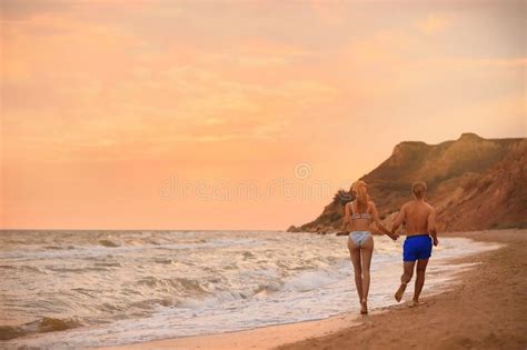 Mujer Joven En Bikini Y Su Novio En La Playa Al Atardecer Hermosa Pareja Foto De Archivo