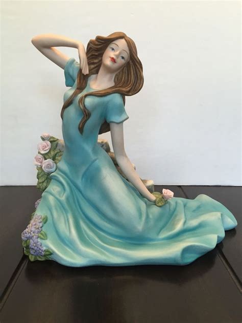 A Figurine Of A Woman Sitting On Top Of A Table