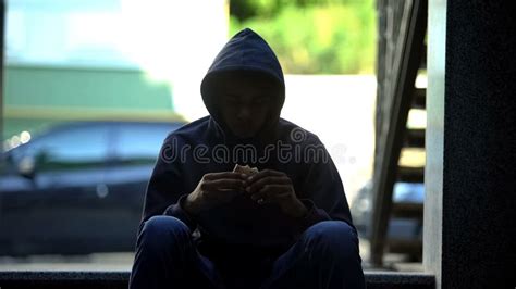 Homeless Hungry Guy Eating Sandwich Sitting In Darkness On Stairs