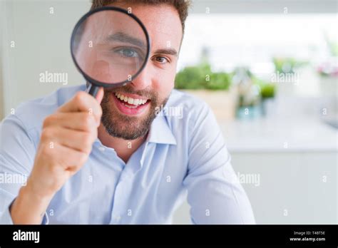 Handsome Business Man Holding Magnifying Glass Close To Face Big Eyes