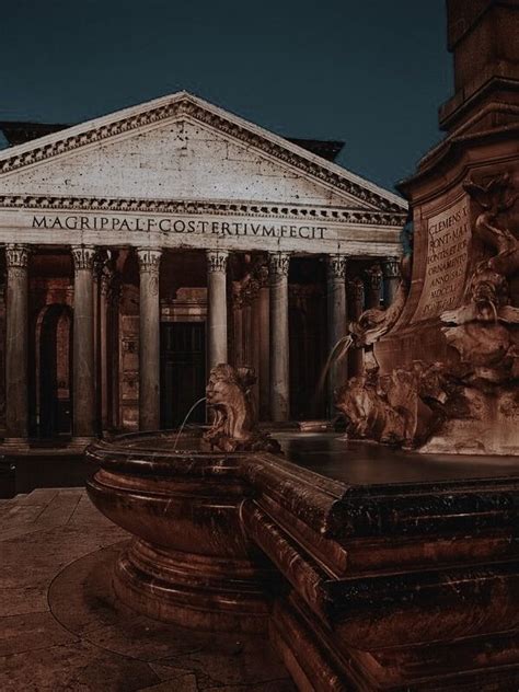 An Old Building With Columns And Statues In Front Of It At Night Or