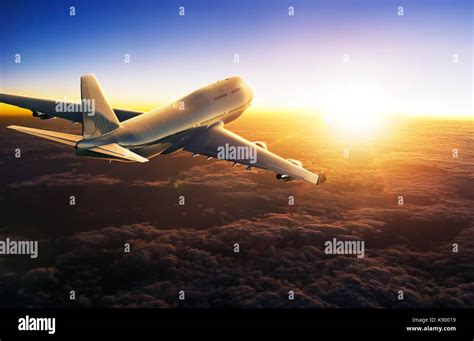 Airplane Flying Above Clouds During Sunset Stock Photo Alamy