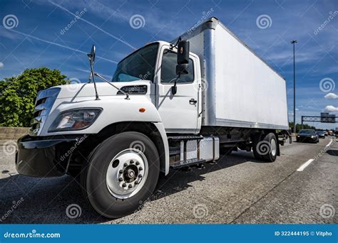 Local Delivery Vehicle Day Cab Big Rig Semi Truck With Box Trailer Running On The Wide Highway