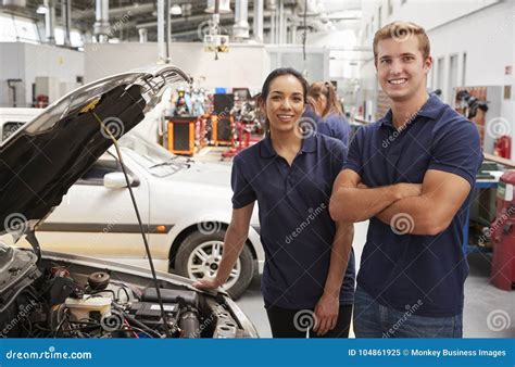 Two Apprentice Mechanics Looking To Camera beside a Car Stock Image