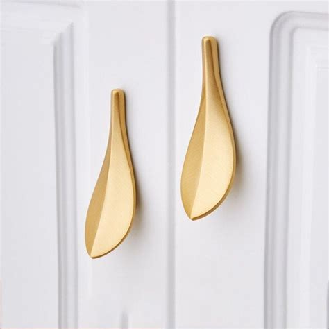 two gold leaf shaped hooks on a white door