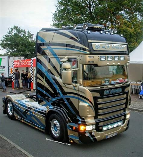 A Large Semi Truck Driving Down A Street Next To A Tent With Tents In