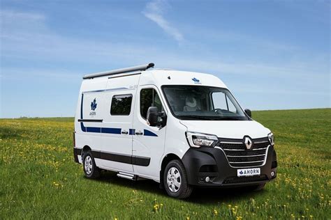 A White Van Parked On Top Of A Lush Green Field Next To A Yellow Flower