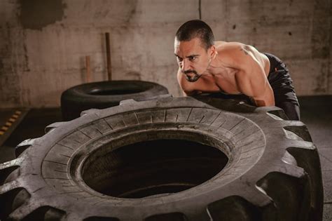 Jovem homem musculoso lançando um pneu no treinamento cross fit no