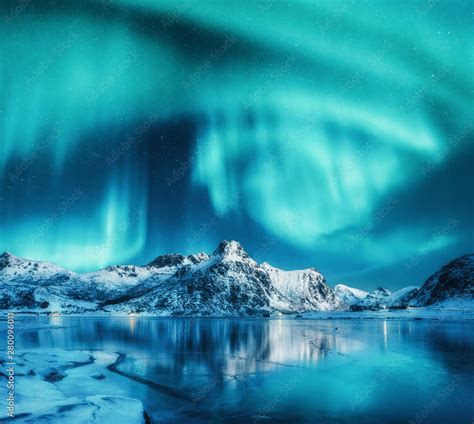 Aurora Borealis Above Snowy Mountains Frozen Sea Coast And Reflection