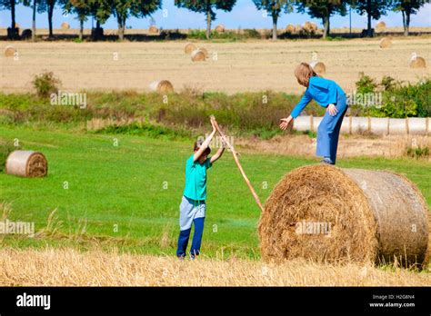 Two Boys Moving Bale Of Hay With Stick As A Lever Stock Photo Alamy