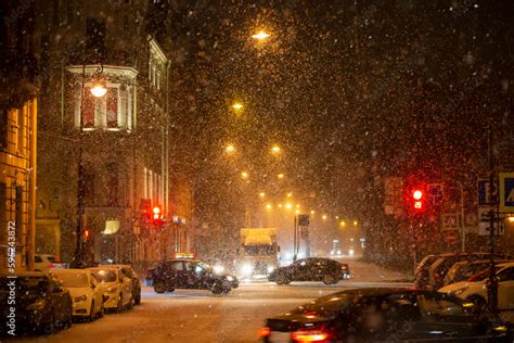 Snow-covered background of the night city with traffic lights and cars ...