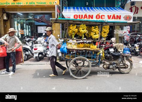 Vietnamese Male Street Vendor Pulling A Cart Selling Bananas On A Road In Ho Chi Minh City