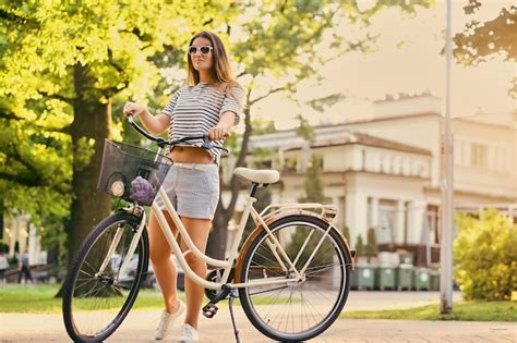 Free Photo Portrait Of An Attractive Brunette Female With A Bicycle In The City Park