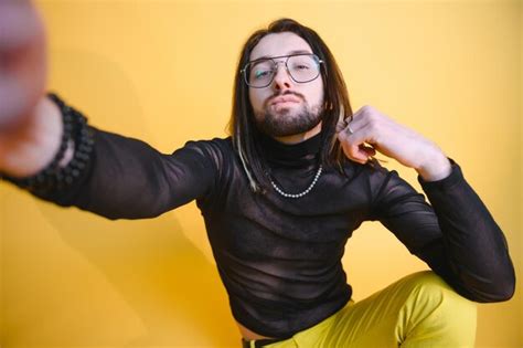 Joven gay está parado en el estudio y posando para una cámara Foto Premium