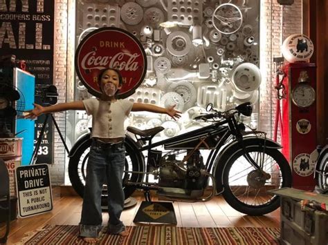 A Woman Standing In Front Of A Coca Cola Motorcycle With Her Arms