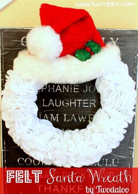 A Christmas Wreath With Santa S Hat Hanging On The Side Of A Chalkboard