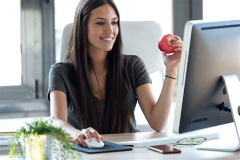 Foto De Mujer De Negocios Joven Sonriente Comiendo Una Manzana Roja