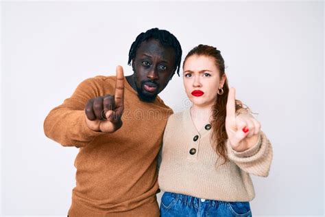 Interracial Couple Wearing Casual Clothes Pointing With Finger Up And