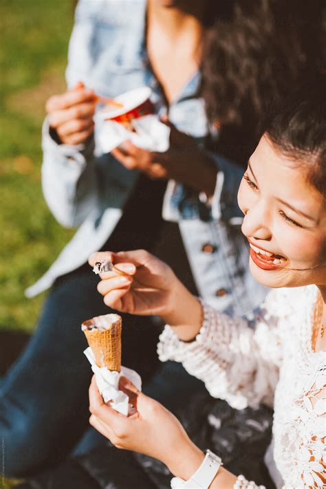 Mixed Race Girlfriends Eating Ice Cream While Having Fun Outdoors By