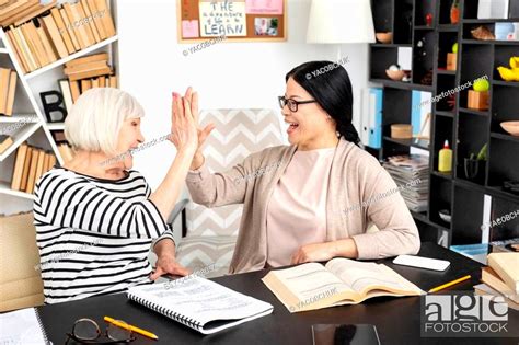 More Knowledge Jolly Mature Tutor And Woman Exchanging High Five While Laughing Stock Photo