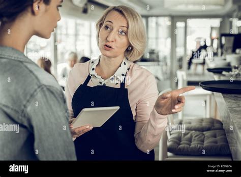 Blonde Haired Owner Of Restaurant Giving Instructions Her Waitress Stock Photo Alamy