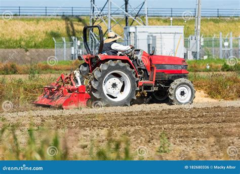 Tractor Rojo Arando La Tierra De Cultivo Del Campo De Arroz Foto De