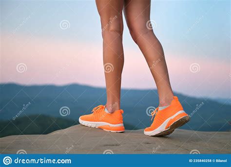 Closeup Of Female Young Slim Legs In Bright Orange Sneaker Shoes