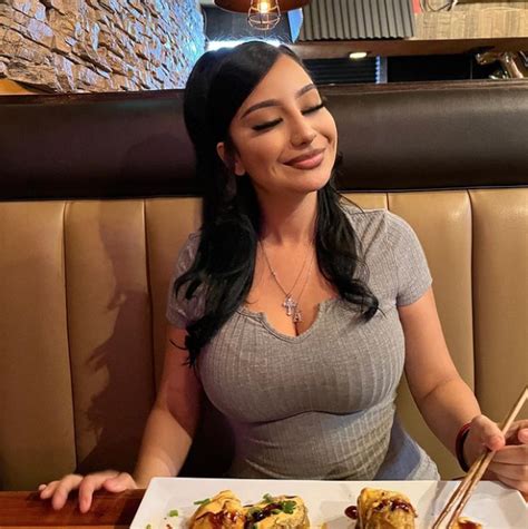 A Woman Sitting At A Table With Food In Front Of Her And Chopsticks