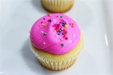 Three Cupcakes With Pink Frosting And Sprinkles On A White Plate