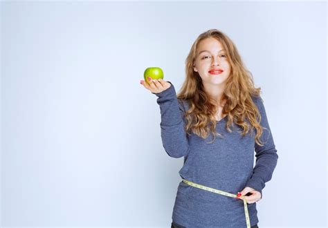 Fille Blonde Montrant Son Tour De Taille Tout En Tenant Une Pomme Verte