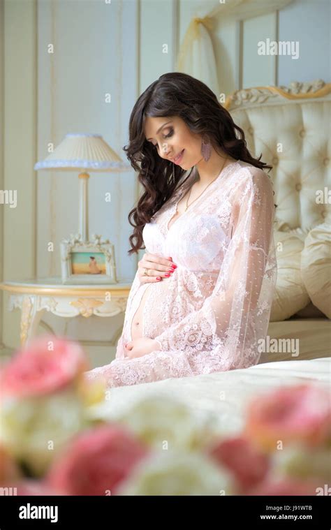 Beautiful Pregnant Girl In A Lace Negligee Sitting On A Bed Of Roses