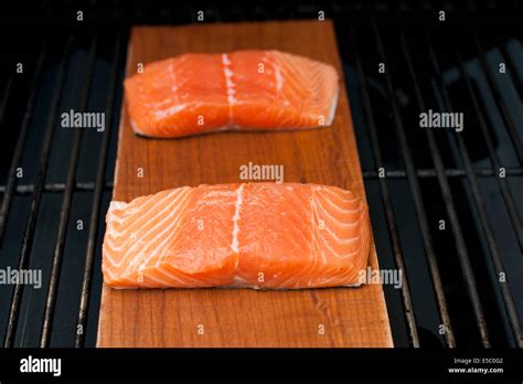 A Pair Of Raw Wild Alaskan Salmon Fillets On A Cedar Plank Being