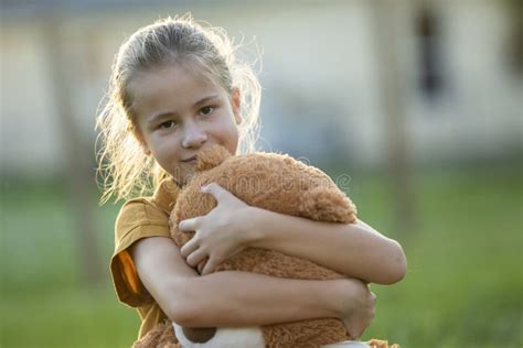 Happy Child Girl Hugging Her Teddy Bear Friend Outdoors On Green Grass