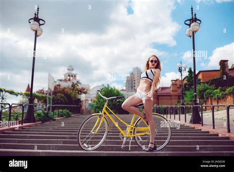 Active Fashionable Blonde Woman Posing Near A Vintage Bike Stock Photo