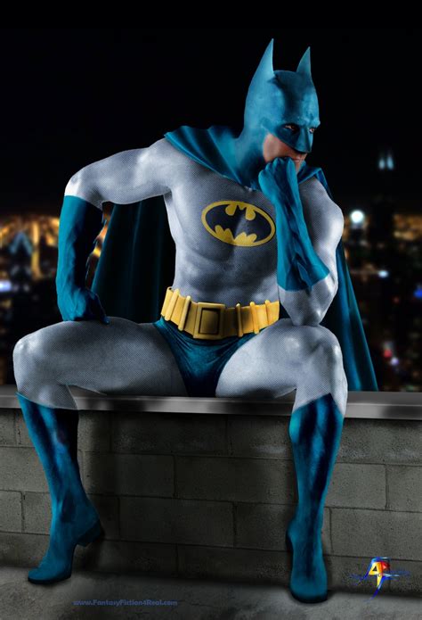 A Man Dressed As Batman Sitting On Top Of A Brick Wall In Front Of A