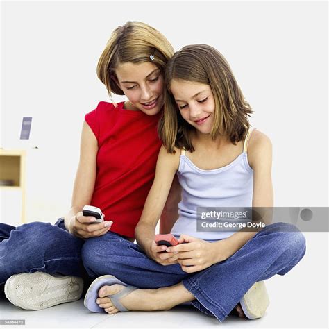 Two Girls Sitting Together Holding Mobile Phones High Res Stock Photo