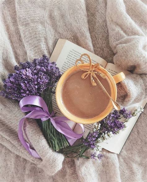 A Cup Of Hot Chocolate Next To Some Lavenders On A Bed With A Book