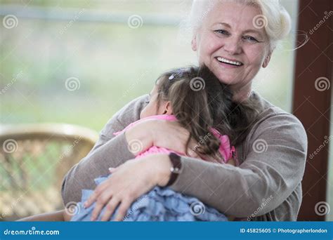 Portrait Of Happy Grandmother Hugging Granddaughter In House Stock