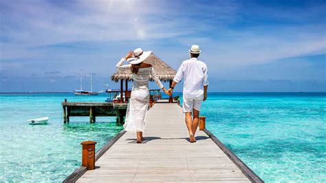 A happy couple in white summer clothing on vacation walks along a ...